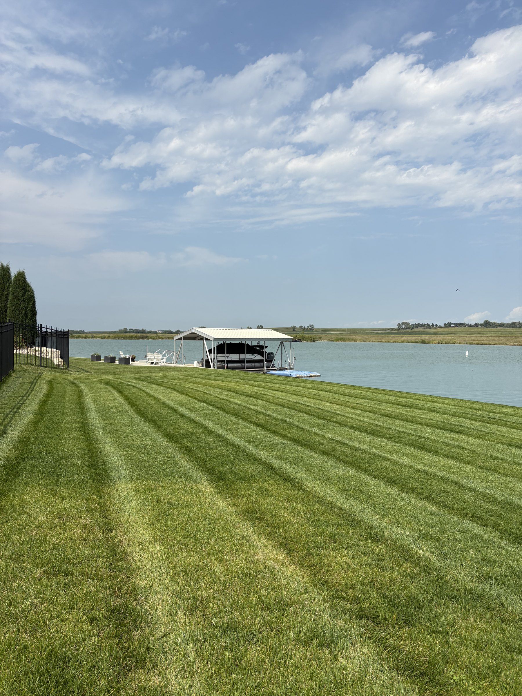 Striped lakefront lawn running down to a boat lift and dock