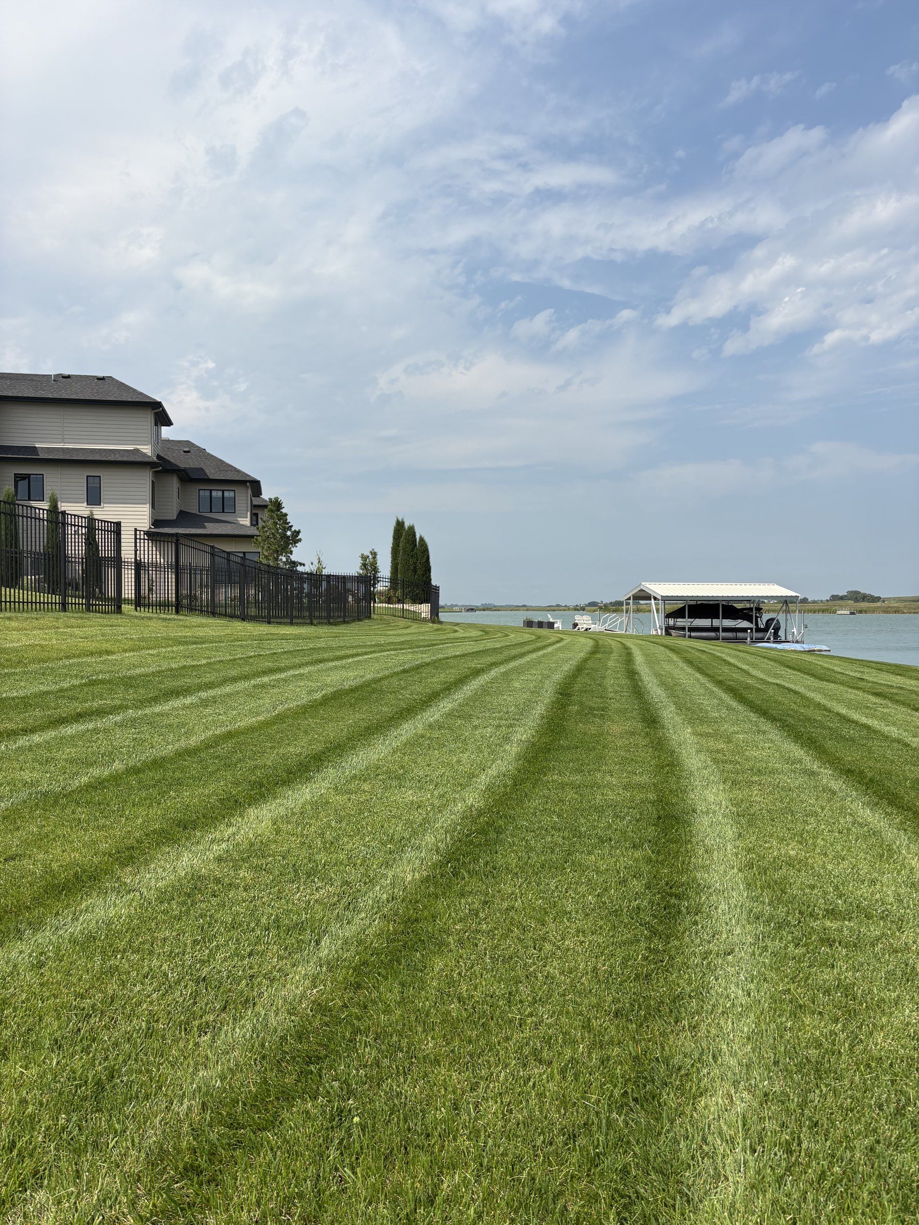 Freshly striped lakefront lawn behind a two-story home, mowed by LSW Scapes
